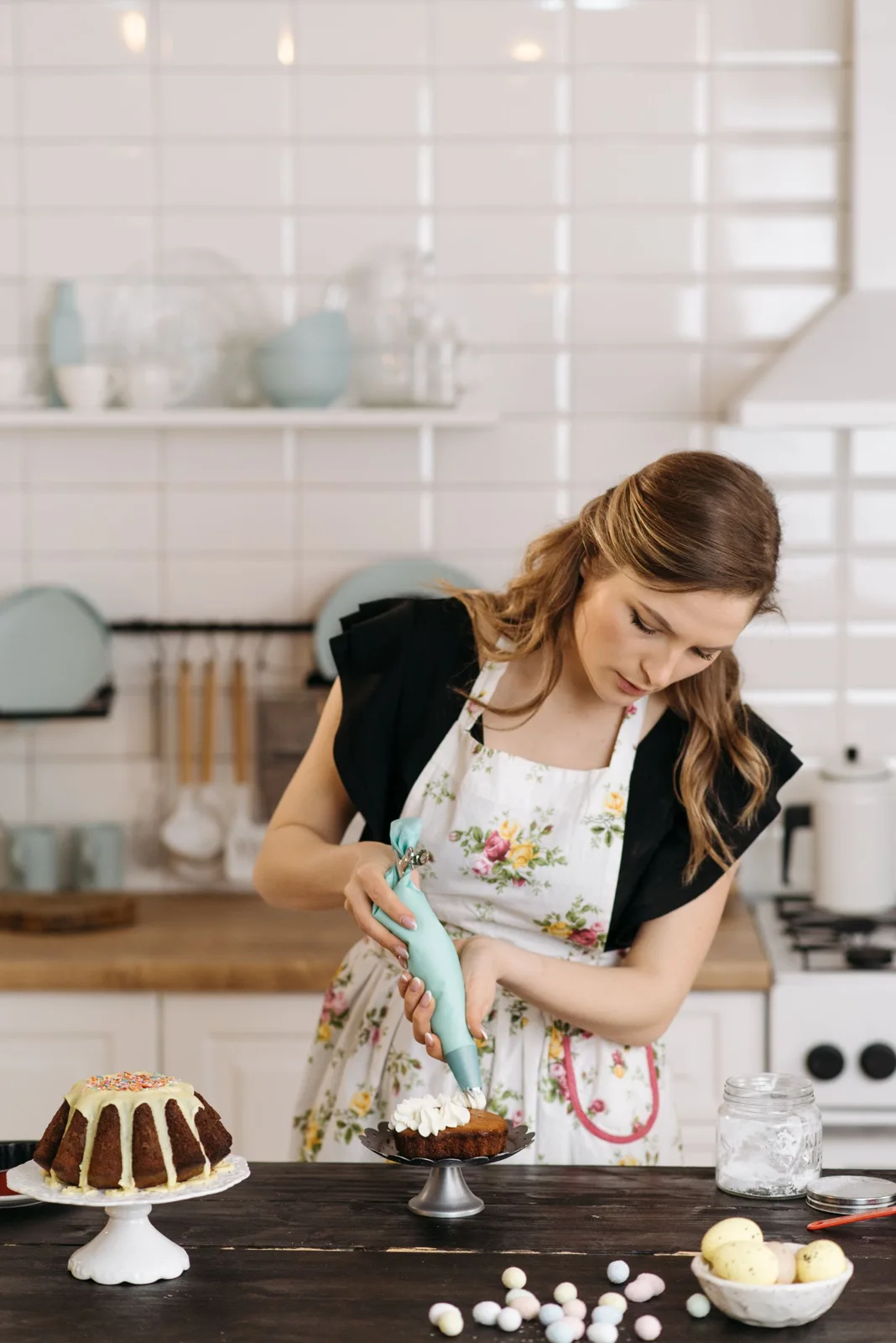 A baker spreading icing on a cake in a kitchen